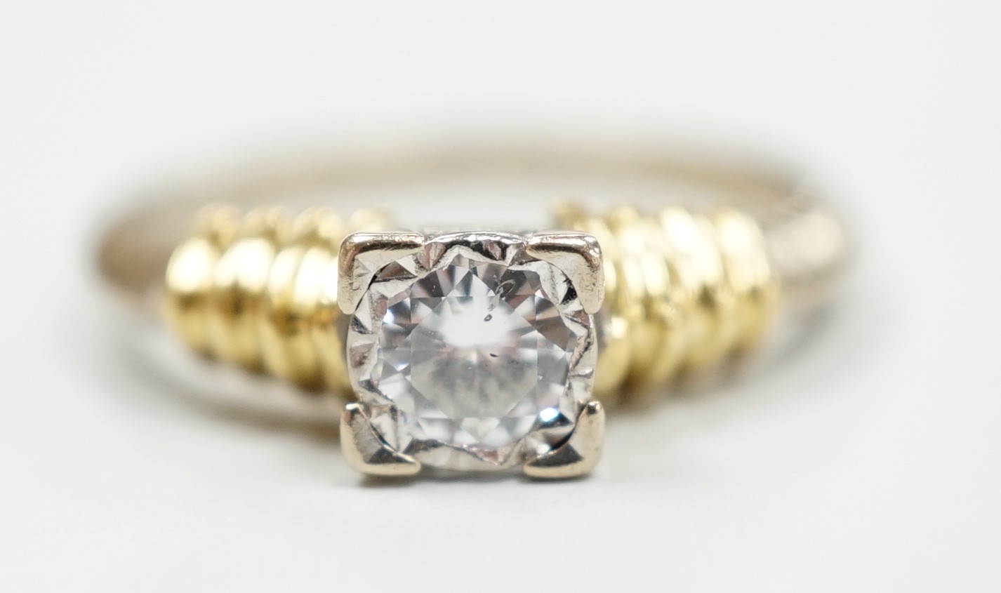 A modern 18ct two colour gold and solitaire diamond set ring, size H/I, gross weight 3.3 grams.